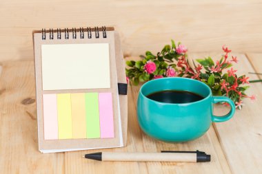 ahşap masa üzerinde Kupası ve vazo ile not defteri