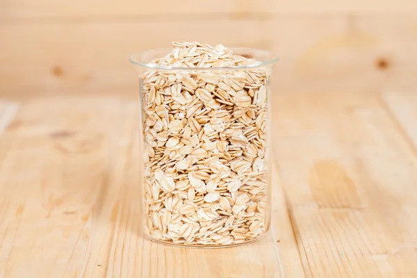 oats flakes pile in bottle on wood background.