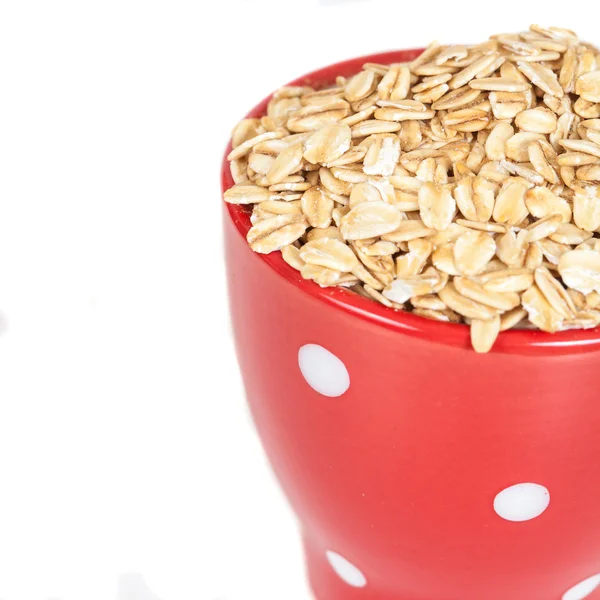 Taza roja con copos de avena pila sobre fondo blanco . —  Fotos de Stock