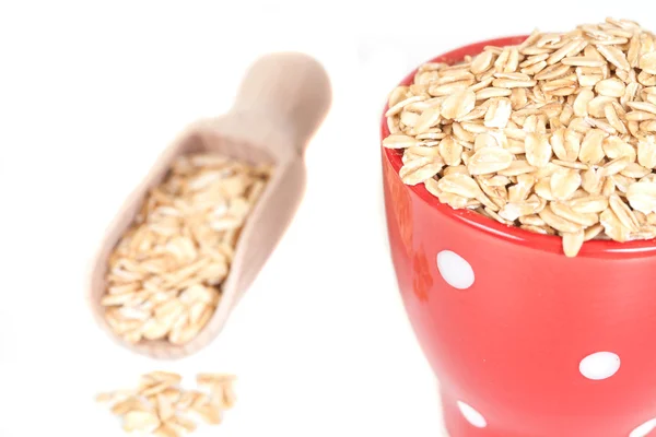 Red cup with oats flakes pile on white background. — Stock Photo, Image