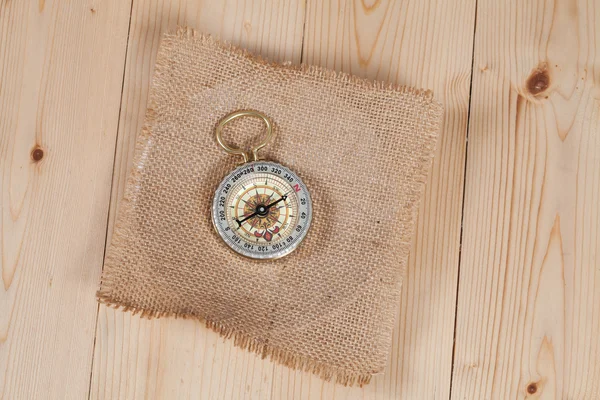 Top view of compass on burlap canvas fabric background. explorer — Stock Photo, Image