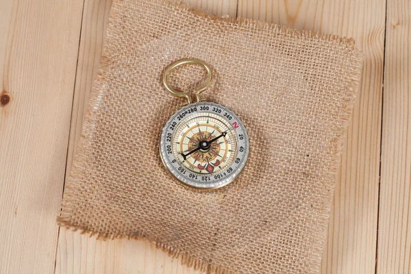 Top view of compass on burlap canvas fabric background. explorer — Stock Photo, Image