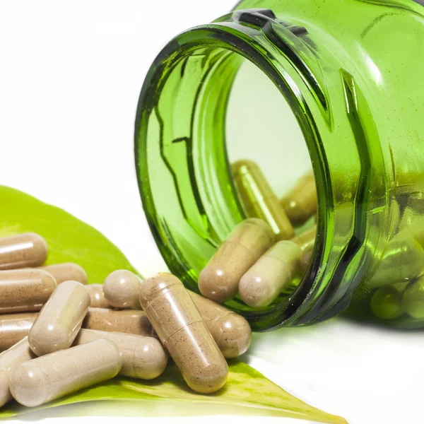 Herb capsules spilling out of a bottle — Stock Photo, Image