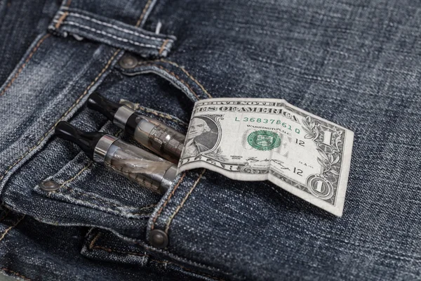 Электронная сигарета и долларовая купюра торчат из джинсового кармана — стоковое фото