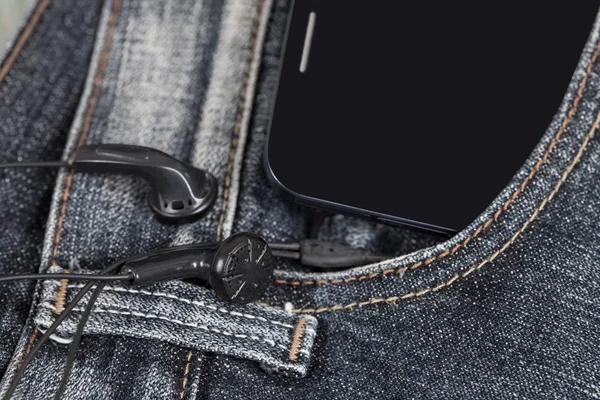 Earphones with mobile smartphone in the pocket old jeans — Stock Photo, Image