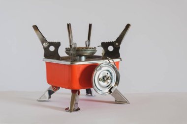 Beyaz arka planda küçük turuncu gaz kamp sobası.