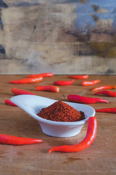 Chili powder and fresh peppers on old wood table background.