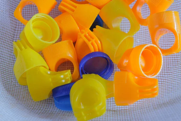 Colorful plastic bottles caps in basket for recycle.