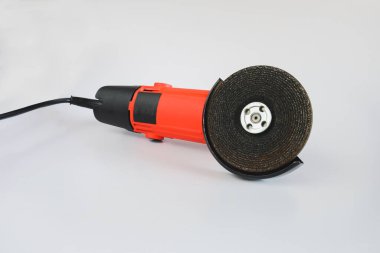 Arkaplanda aşındırıcı diski olan güçlü açı öğütücü.