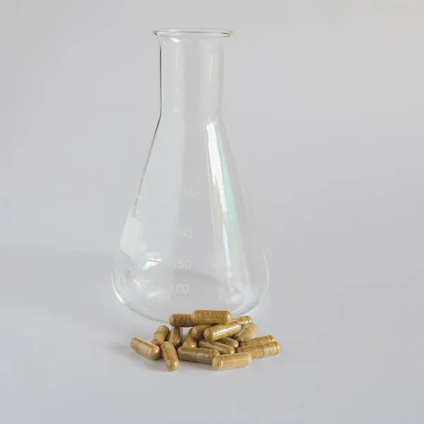 医学概念 带有散落草药胶囊丸的科学瓶 — 图库照片