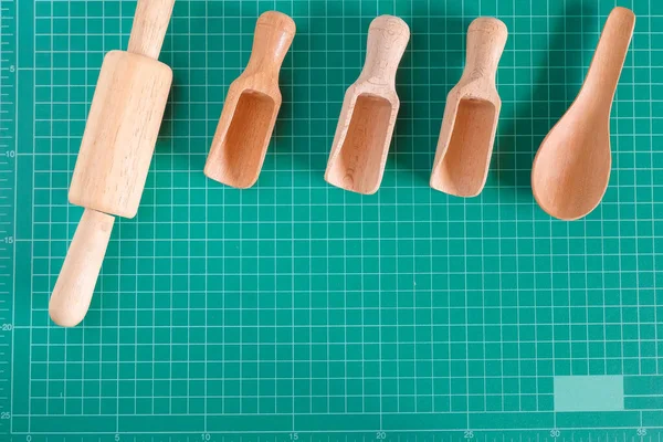 Kitchenware and wood spoon on cutting mat background.