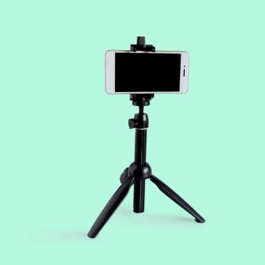 Beyaz arkaplanda cep telefonu için mini tripod.