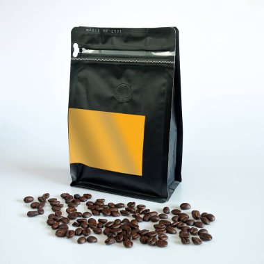 Arka planda siyah ambalajla kavrulmuş kahve çekirdeği..