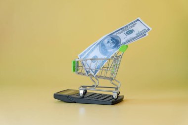 Arkaplanda hesap makinesi üzerinden alışveriş arabasındaki banknot.