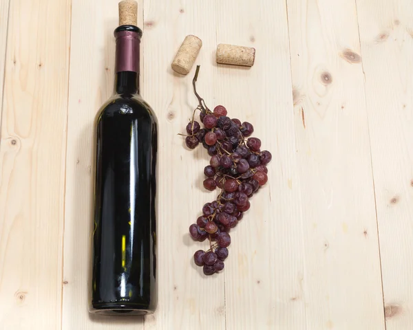 Bottle of old wine, sear grape and corks on wooden table — Stock Photo, Image