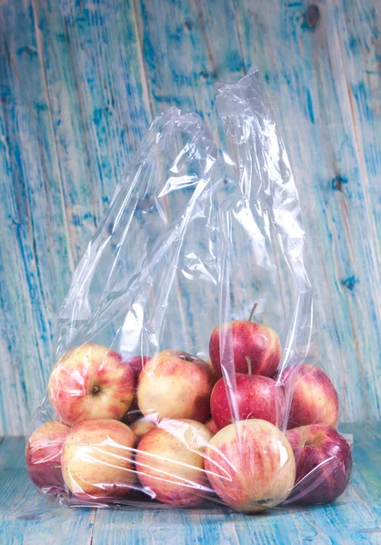 Apple i plastpåse på trä — Stockfoto