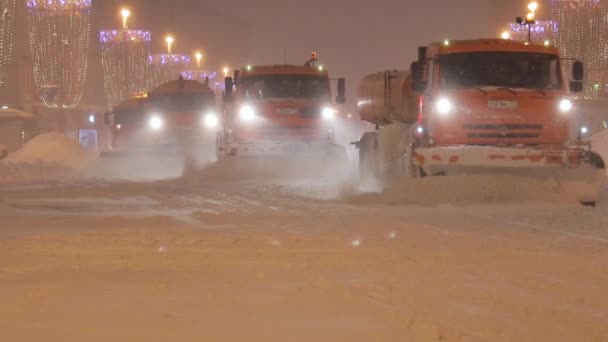 Grande queda de neve. Há muitos snowblowers dirigindo ao longo da rua. Tiro noturno — Vídeo de Stock