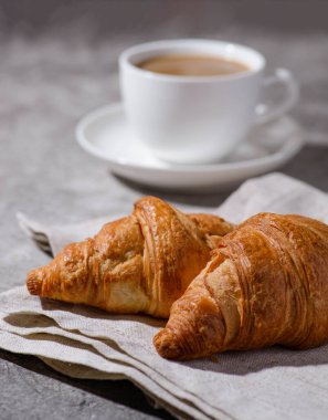 Gri arka planda kruvasanlar ve bir fincan kahve. Yüksek kalite fotoğraf