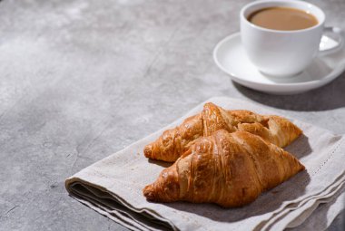 Gri arka planda kruvasanlar ve bir fincan kahve. Yüksek kalite fotoğraf