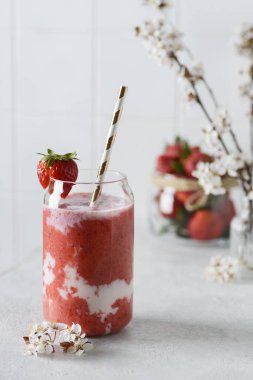 Beyaz arka planda çiçekli çilekli smoothie.