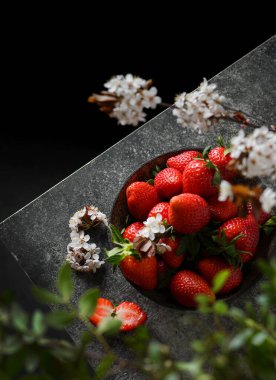 Koyu arkaplanda bir tabaktan çilekler.