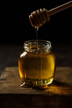 Tahta üzerinde bal kaşığı olan bir kavanoz bal. Yüksek kalite fotoğraf, düşük kalite siyah yemek fotoğrafı.