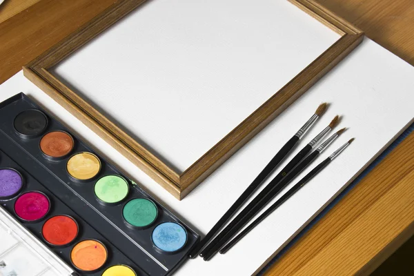 Aquarel set, houten frame en borstels op witte album achtergrond. — Stockfoto