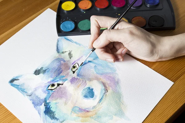 De kunstenaar schildert een beeld Wolf met behulp van borstel en aquarel schilderij kleurrijke set. — Stockfoto