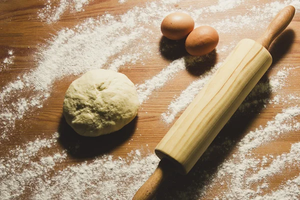 Huevos, rodillo y masa en la mesa de madera de la cocina . — Foto de Stock