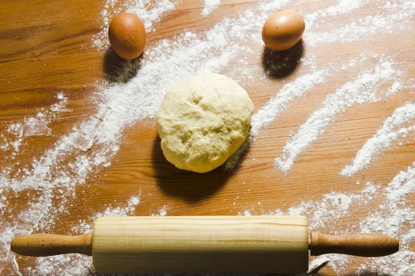 Huevos, rodillo y masa en la mesa de madera de la cocina . — Foto de Stock