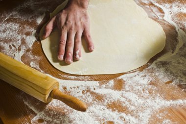 Adam oklava kullanarak Ahşap mutfak masasında pasta rulo.