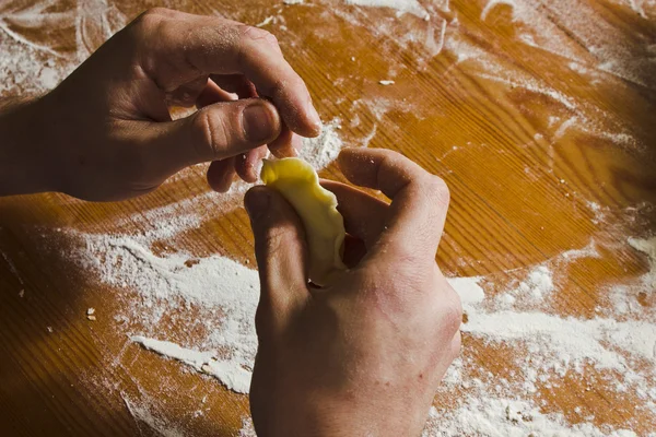 Male shapes dumplings with potatoes  on the wooden table. — Stock Photo, Image