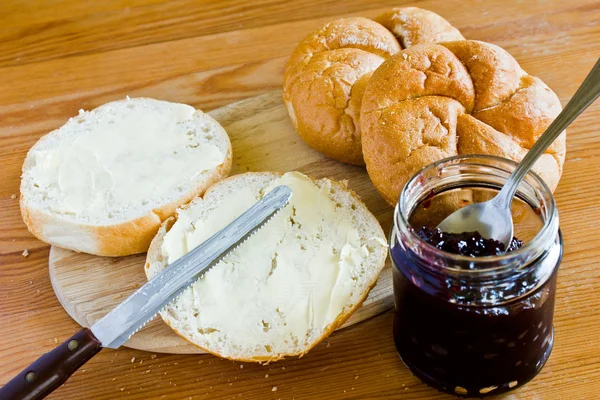 Runda bullar sylt smör och vinbär på en trä facket bakgrund. — Stockfoto