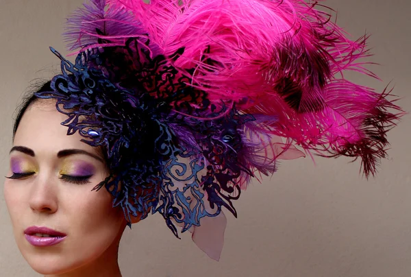 Close-up portrait of beautiful young woman in lace lilac purple hat fascinator with feathers on grey background. — Stock Photo, Image