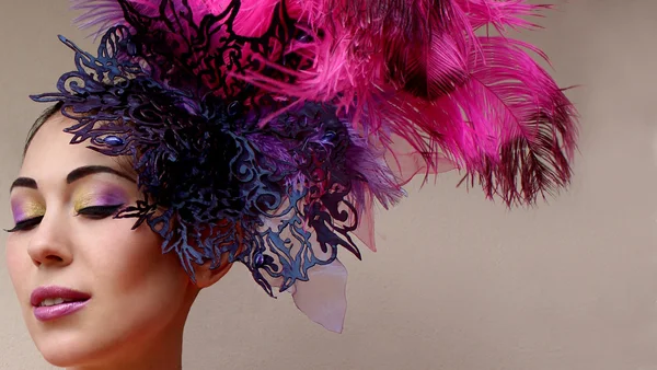 Close-up portrait of beautiful young woman in lace lilac purple hat fascinator with feathers on grey background. — Stock Photo, Image