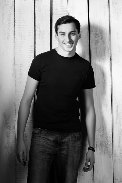 Joven hombre guapo con camiseta y vaqueros en el fondo tablones de madera. Estilo casual . — Foto de Stock