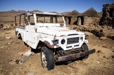 Kimliği belirsiz kırık terk edilmiş beyaz araba arka plan etnik Afrika rondavels terk edilmiş köyün yanındaki Sani geçmek, Lesotho.
