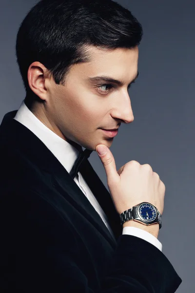 Retrato de cerca de un joven guapo y elegante en traje y camisa blanca con reloj sobre fondo blanco. Modelo de moda estudio de rodaje. Cara de perfil. Hombría y sexualidad. Estilo de negocio de lujo . — Foto de Stock