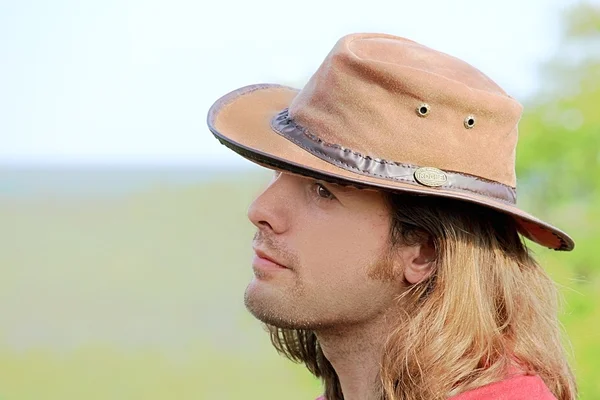 Yakın çekim yakışıklı olan kovboy şapkalı uzun saçlı portresi. Safari. Romantizm. Ülke stil. — Stok fotoğraf