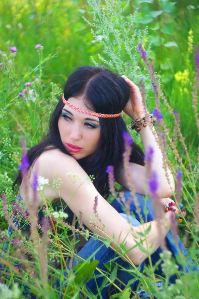 Schöne junge Frau Hippie posiert draußen. Modelshooting. Bohème-Stil. Boho-Chic. Natur genießen. Gesundes Lächeln. Mädchen in grünem Gras und Blumen. — Stockfoto