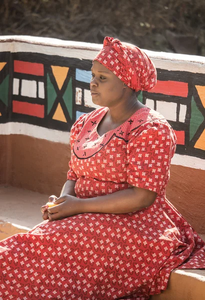 Zuid-Afrika, Gauteng, Lesedi cultureel dorp (unieke centrum van Afrikaanse cultuur) - 04 juli, 2015. Ndebele vrouw Bantoe in traditionele handgemaakte etnische rood witte jurk en hoed. — Stockfoto