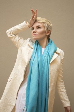 Şık güzel genç kadın sarışın mavi eşarp ve izole bej renkli arka plan üzerinde beyaz desen ceket giyiyor. Kısa saçlı kız. Profesyonel çıplak makyaj. Moda taze makyaj. Çekim modeli. Zarif stili.