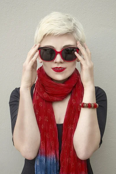 Stylový portrét blondýnka mladá krásná žena v červeným šátkem a sluneční brýle, izolované na šedém pozadí. Dívka s krátkými vlasy. Módní účes. Módní účes. Model trefa. Módní doplňky — Stock fotografie