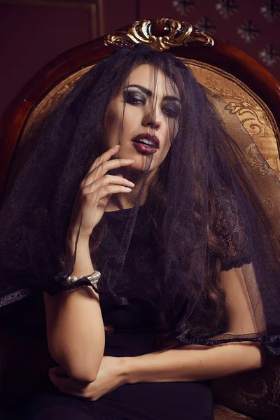 Mysterious young beautiful woman in black transparent lace veil, evening dress sitting in vintage chair. Accessories pearl bracelet. Fashion make-up smoky eyes. Black and white shades. luxury. Sexuality. Seduction. Sensuality. — Stock Photo, Image