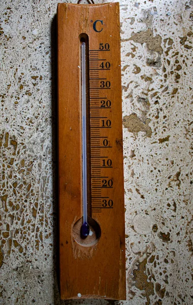Blue liquid environmental thermometer, old but in perfect working order. Wooden base on a marble background