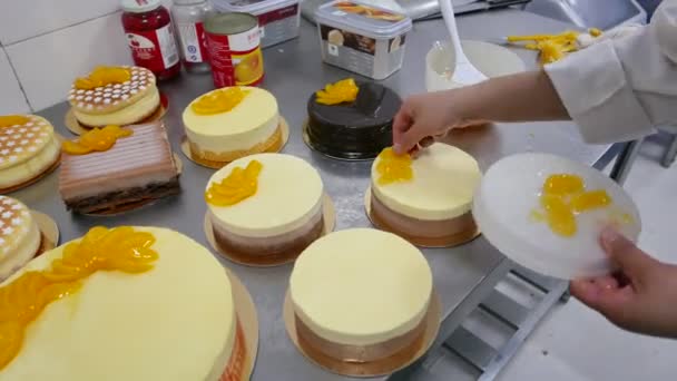 在一家面包店的蛋糕糕点厨师添加橙片 — 图库视频影像