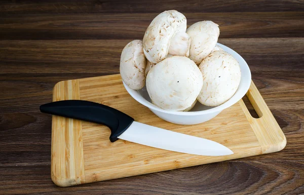 White mushrooms in the bowl with a ceramic knife — Stock Photo, Image