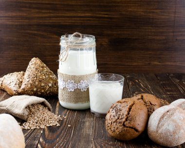 İnek sütü ve buğday rulo bir torba koyu ahşap bir masa üzerinde.