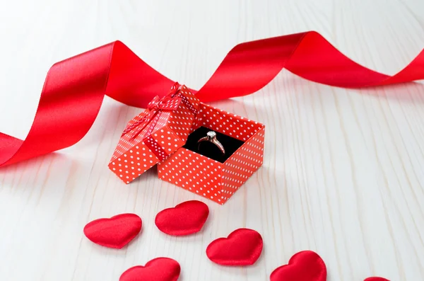 红色礼品盒与金戒指 背景上的心和丝带 — 图库照片