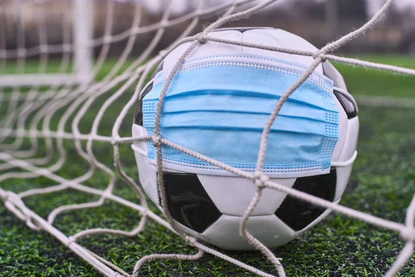Futbol topu tıbbi maskeli Gol Ağı 'nda. Boş Stadyum. Futbol Yarışmalarının İptal Edilmesi